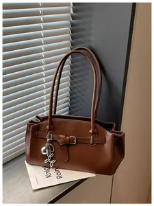 Close-up of a brown pebbled faux-leather underarm bag with a silver balloon dog charm