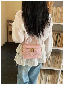 Primer plano de un mini bolso rosa tipo caja con detalles trenzados en la espalda