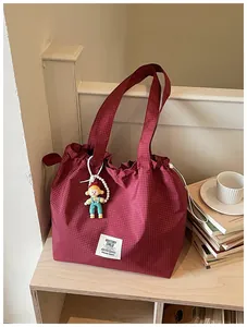 Large red checkered canvas tote bag featuring a decorative doll keychain and brand label.