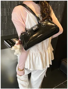 Gros plan d'un sac sous les bras vintage noir brillant avec breloque ours et détails argentés.