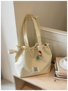 Detailed view of cream canvas tote bag with drawstring closure and cute doll charm