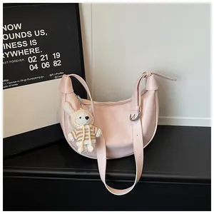 Detail of a pink crescent crossbody bag featuring a cute plush rabbit charm accessory.