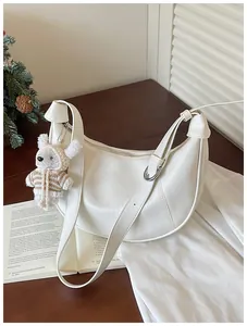 Minimalist white crescent hobo bag featuring a charming plush bear pendant accessory