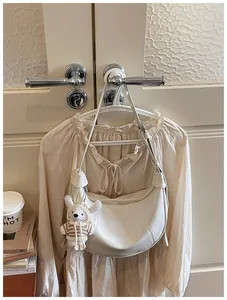Detailed view of a cream-colored dumpling crossbody bag with a plush rabbit charm