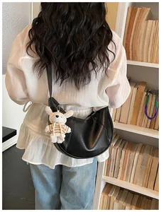 Casual black crescent crossbody dumpling bag featuring a cute white plush dog charm
