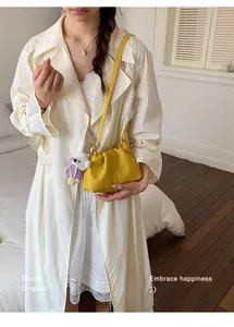 Detalle de un elegante bolso bandolera amarillo fruncido con un colgante de conejo.