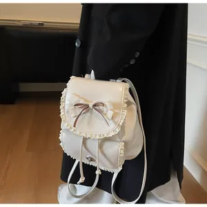 Detail showing cream faux leather mini backpack with lace and bow decoration in use.