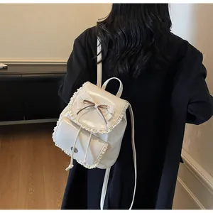 Detailed close-up view of a white lace-trimmed backpack with bow on dark blazer background