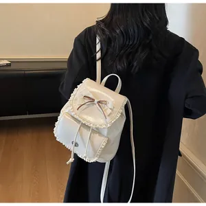 Back view of an elegant white mini backpack with lace trim and bow detail on a model