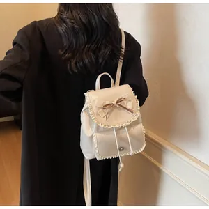 Close-up of elegant cream white lace bow backpack on a model wearing a chic black blazer