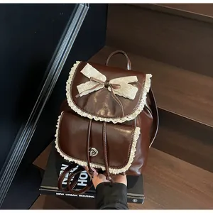 Close-up of a vintage brown leather backpack with lace trim and bow knot detail on stairs.