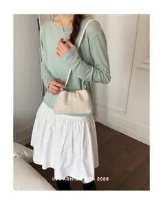 Elegante bolso de hombro blanco roto llevado por una modelo con camisa verde.