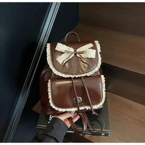 Close-up detail of a brown leather backpack featuring elegant white lace trim and bow