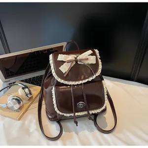 Elegant dark brown leather backpack featuring delicate white lace trim and a large bow