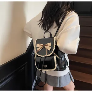 Elegant black PU leather backpack with lace trim and bow worn by a model on stairs