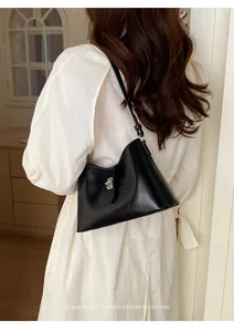 Vista dettagliata di una modella che indossa una borsa sottobraccio nera minimalista