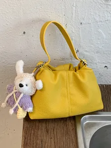 Bolso tipo cubo de cuero amarillo texturizado con un adorable colgante de osito de peluche