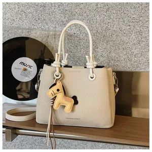 Stylish cream bucket bag with cute horse charm and adjustable shoulder strap.