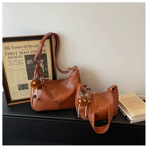 Pair of vintage brown leather hobo bags with cute monster charms in retro setting.
