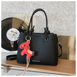 Close-up of black bucket bag with circular handles and red horse leather charm
