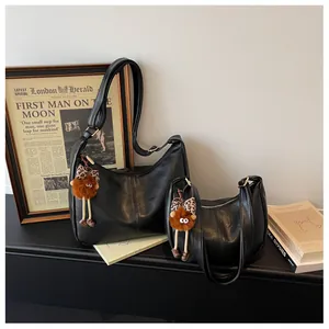 Stylish black leather hobo shoulder bags in two sizes featuring cute monster bag charms
