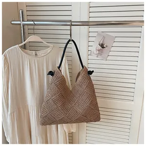 Chic sac hobo en paille tissé à la main pour les vacances sur un portant à vêtements