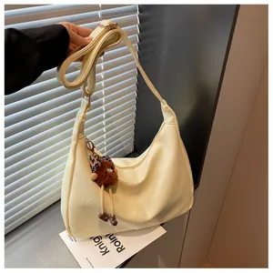 Cream-colored hobo shoulder bag with a cute brown furry doll charm and adjustable strap