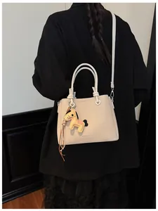 Detailed close-up of a stylish beige canvas bucket bag with horse charm on a model