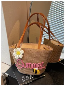 Detailed macro view of a straw beach bag with Summer embroidery and flower charm.