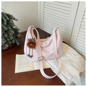 Detailed view of a soft pink hobo bag featuring a cute fur charm and adjustable strap