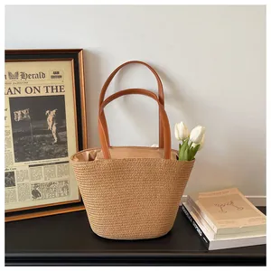 Close-up detail of a handmade woven straw bucket bag with brown leather handles