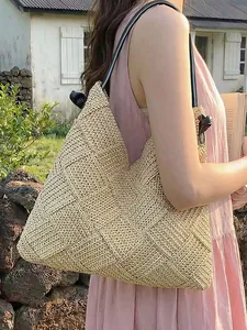 Grand sac fourre-tout en paille tissé à la main pour les vacances avec des anses noires.