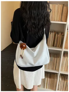 Large capacity off-white shoulder bag with fuzzy charm shown from a lifestyle back view