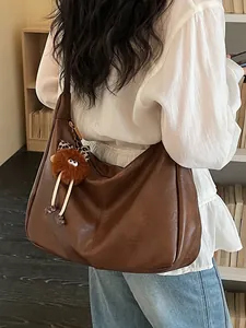 Large brown vegan leather hobo shoulder bag for women with cute plush monster charm