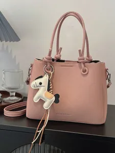Elegant pink bucket handbag featuring a cute horse charm and adjustable crossbody strap