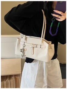 Detail shot of cream white textured leather shoulder bag with balloon dog keychain