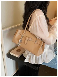 Close-up detail of a beige textured leather underarm bag featuring a silver rabbit charm