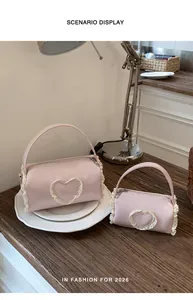 Detailed view of two sizes of pink cylindrical handbags with lace heart embellishments