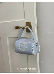Mini light blue barrel handbag with white lace heart detail hanging on a door handle