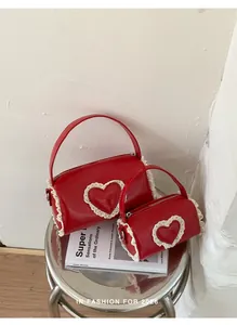 Close-up view of mini red cylinder handbags with elegant lace heart details and handles.