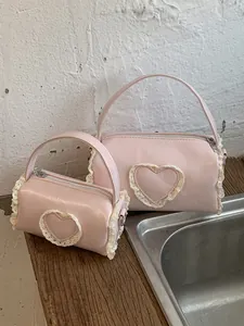 Two pink mini cylindrical handbags featuring lace heart design and crossbody strap