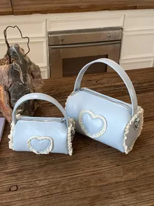Pair of light blue cylindrical handbags featuring lace heart design in two different sizes