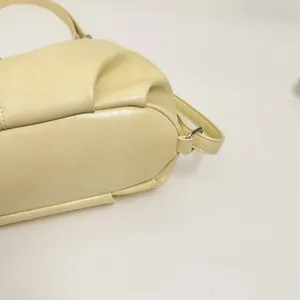 Dettaglio ravvicinato della trama in pelle beige, cuciture e anello del cinturino