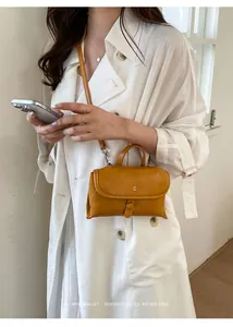 Detail van een minimalistische gembergele kleine crossbodytas met XX-logo.