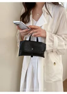 Chique zwarte mini-handtas van getextureerd leer in een minimalistische retro-stijl