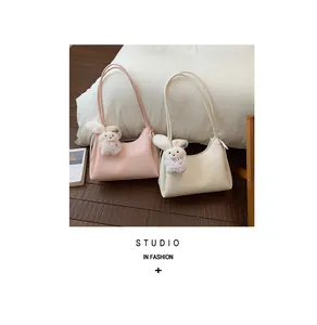 Zwei minimalistische Unterarmtaschen in Rosa und Creme mit süßem Hasenanhänger.