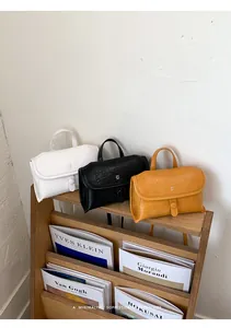 Gedetailleerde weergave van drie minimalistische kleine handtassen in wit zwart geel