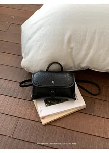Detailweergave van een zwarte crossbodytas van leer met een minimalistisch XX-logo.