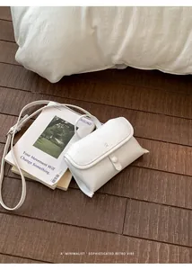 Detailopname van een witte minimalistische crossbodytas op een rustieke houten vloer