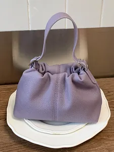 Bolso tipo cubo fruncido color lavanda con textura de guijarros y asa.